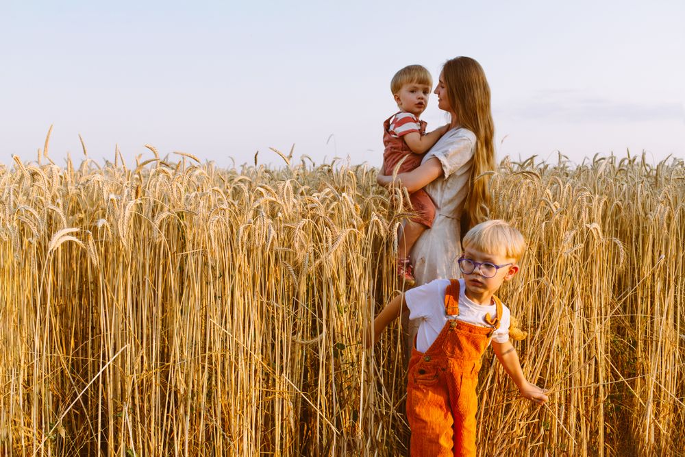 Young mother with little sons standing on wheat field in countryside
