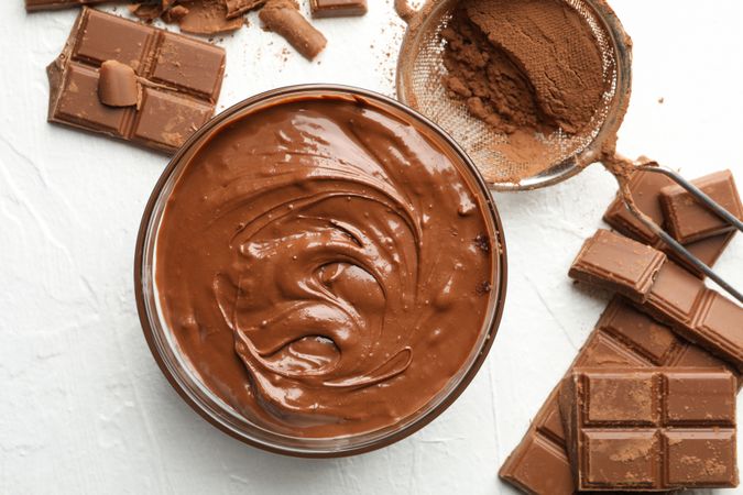 Chocolate, melted chocolate and powder on light background