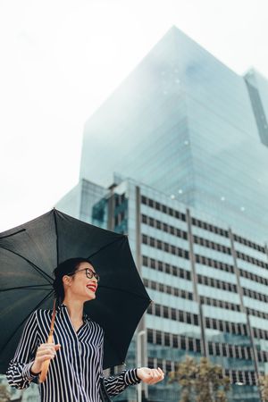 Woman standing outdoors in the city holding umbrella and smiling