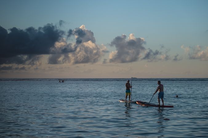 Two people paddle boarding at dusk