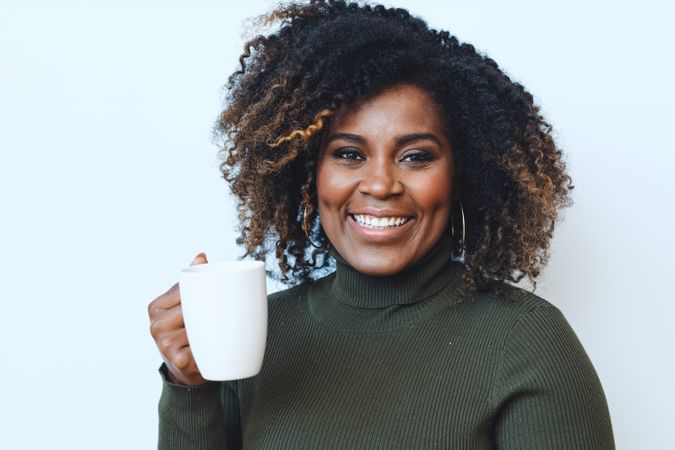 Black woman smiling holding a cup of coffee