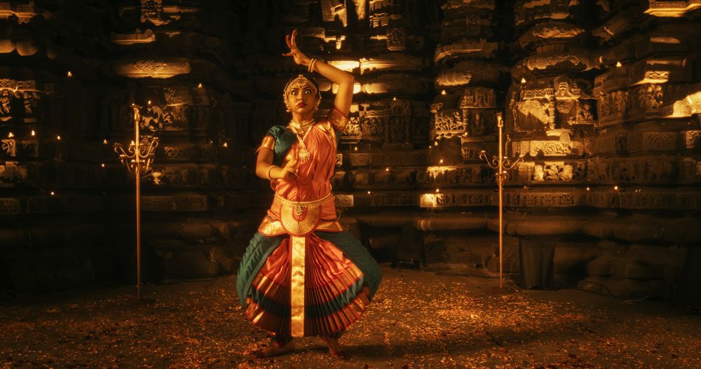 Portrait of Young Energetic Indian Woman Performing Traditional Folk Dance Inside a Candle-Lit Temple.