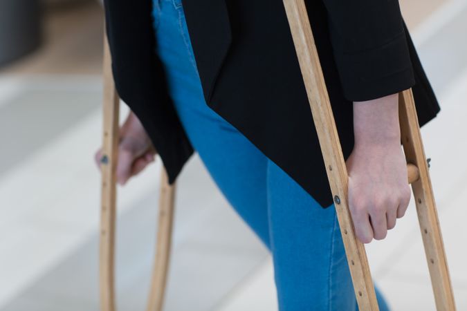 Cropped image of a person walking with crutches