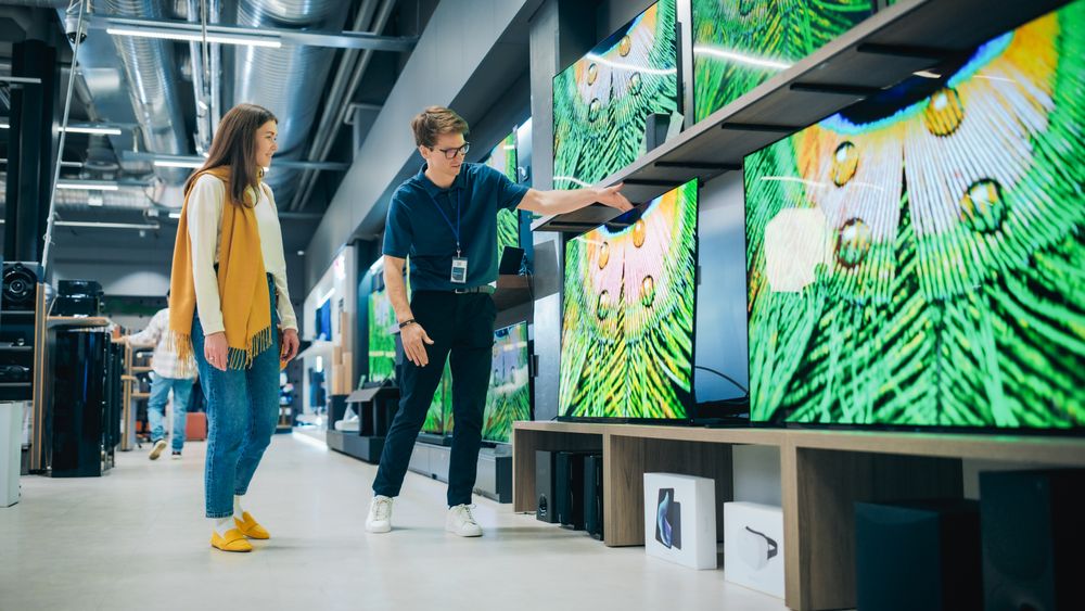 Client Engaging in Dialogue with Retail Electronics Shop Consultant.