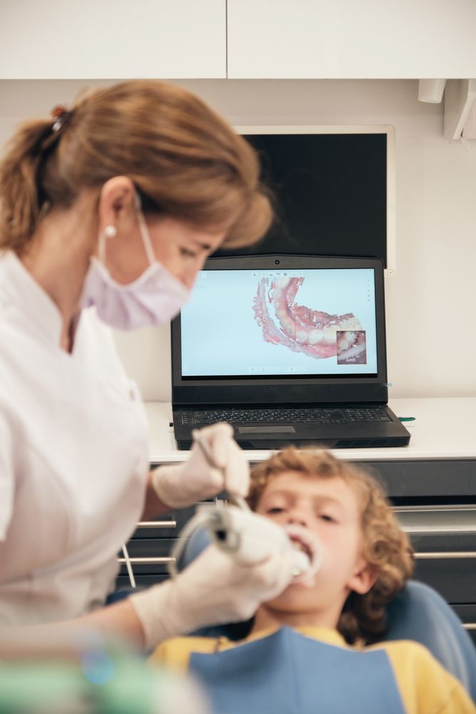 Dentist applying intraoral scanner to boy for displaying teeth casts
