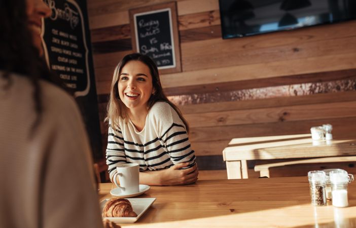 Smiling woman sitting in a restaurant talking to her friend
