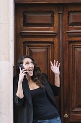 Young female using mobile phone on wooden door