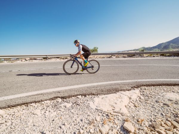 healthy man riding a bicycle on a mountain road in a sunny day