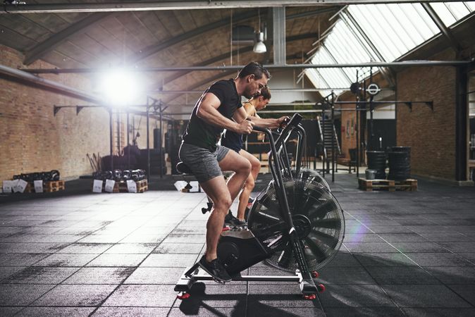 Two fit people on indoor cycling bikes in brick warehouse gym