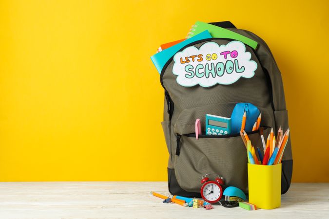 Text Let's go to school and school supplies on yellow background