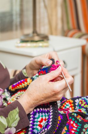 Hands of woman knitting a vintage wool quilt
