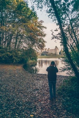 Back view of a man standing beside lake