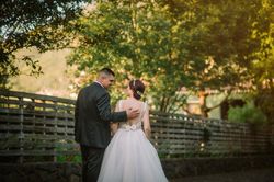 Smiling groom and bride hugging and kissing in park