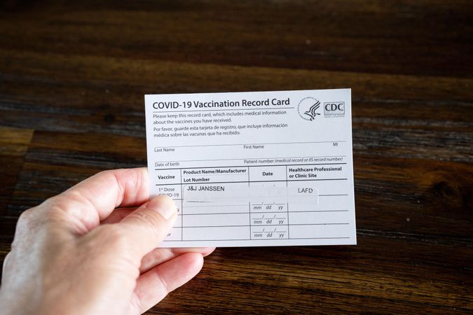 Close up of a hand holding COVID vaccination card