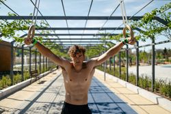 Strong young sportsman exercising with rings