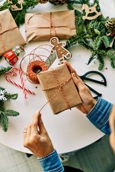 Crop person opening Christmas gift box above table