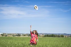 Young woman throwing up hat in field