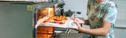 Banner of unrecognizable professional cook putting pizza into oven in restaurant kitchen