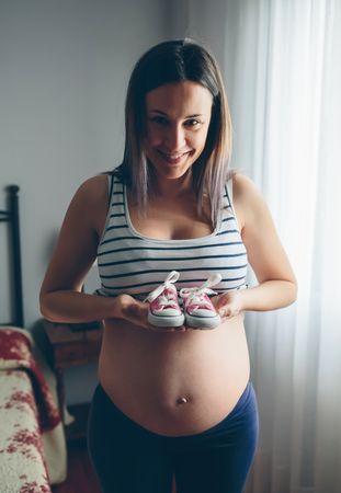Pregnant showing baby sneakers