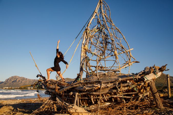 Young woman on decorative wooden ship near water on shore