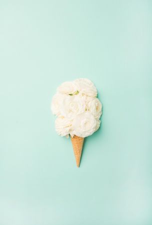 Waffle cone with fresh light flowers  on a pastel green background