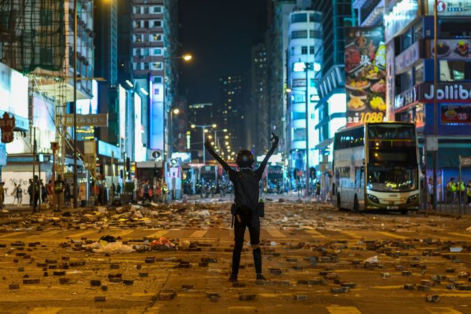 Back view of a person standing in the middle of street full of gas canisters during Hong Kong's protest