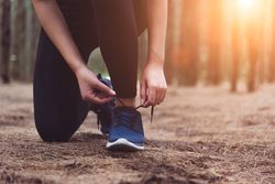 Woman tying shoe laces in forest