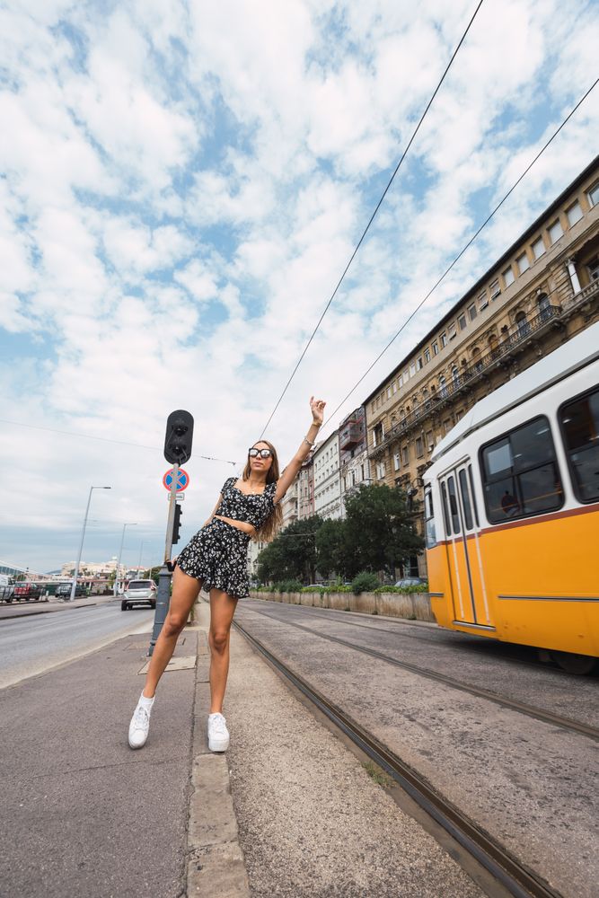 Stylish woman stopping tram with raised hand
