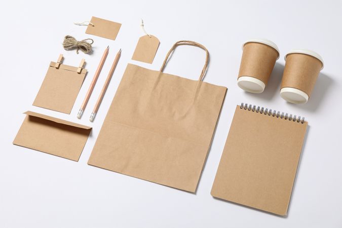 Composition with blank stationery, paper cups and bag on blank background, mockup