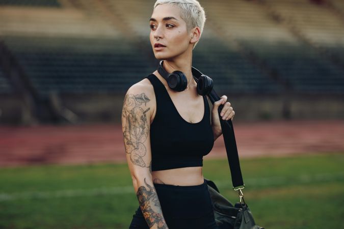 Female athlete walking in a track and field stadium carrying her gym bag