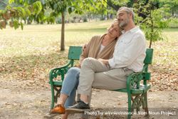 Male and female older couple relaxing together on park bench bGyDx5