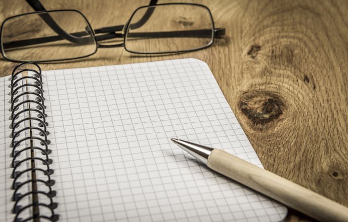 Maths notebook and eyeglasses on wooden desk