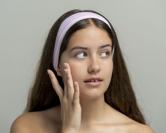 Skin examination: young woman touching cheek in gentle skincare, facial beauty with natural look.