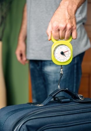 Man checking luggage weight with steelyard balance