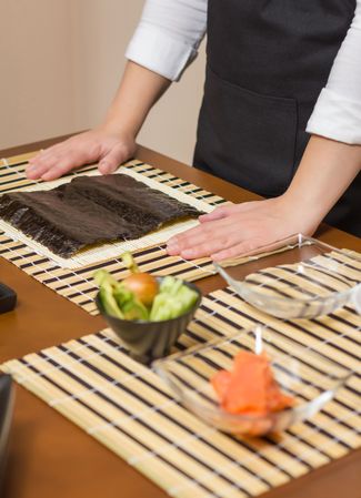 Hands of chef ready to prepare Japanese sushi rolls, vertical