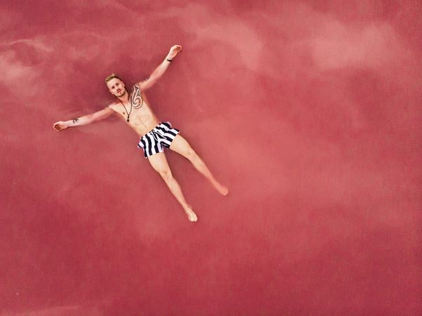 Carefree man on vacation delighting in pink water of lake