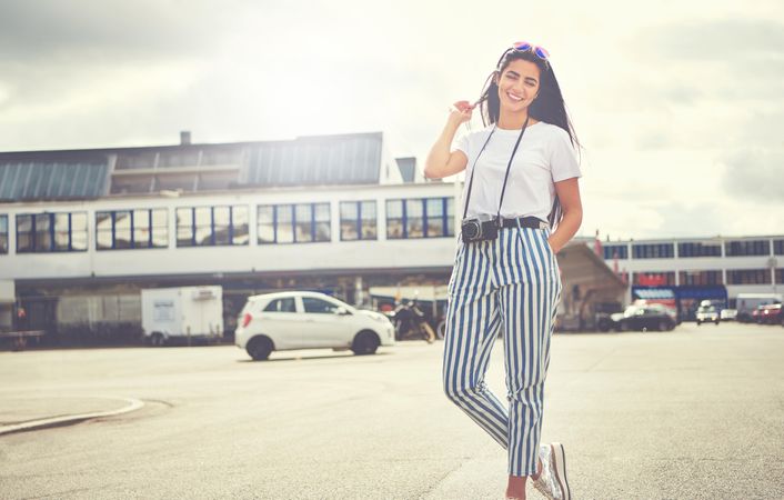Woman playing with hair walking among cars in the back of a building