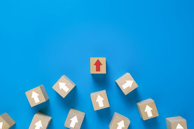 wooden blocks with irregular arrows and one red arrow pointing right direction isolated on blue background. leadership concept