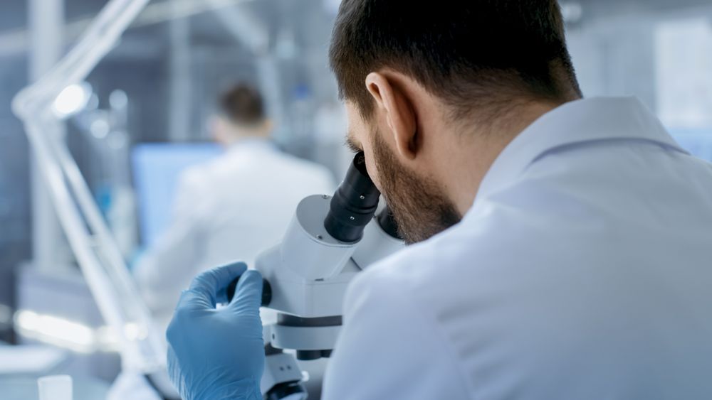Over the Shoulder View of a Research Scientist Looking into Microscope.