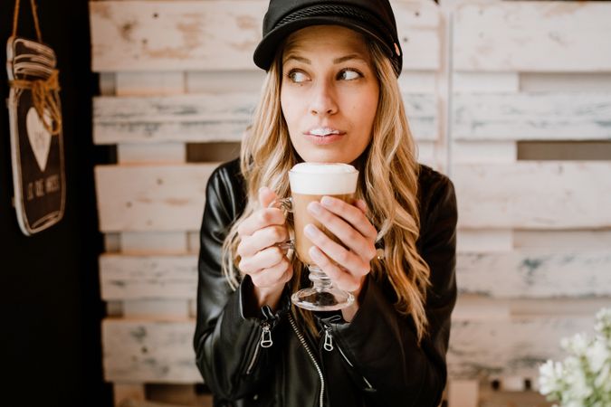 Stylish woman holding coffee in hands and licking lips