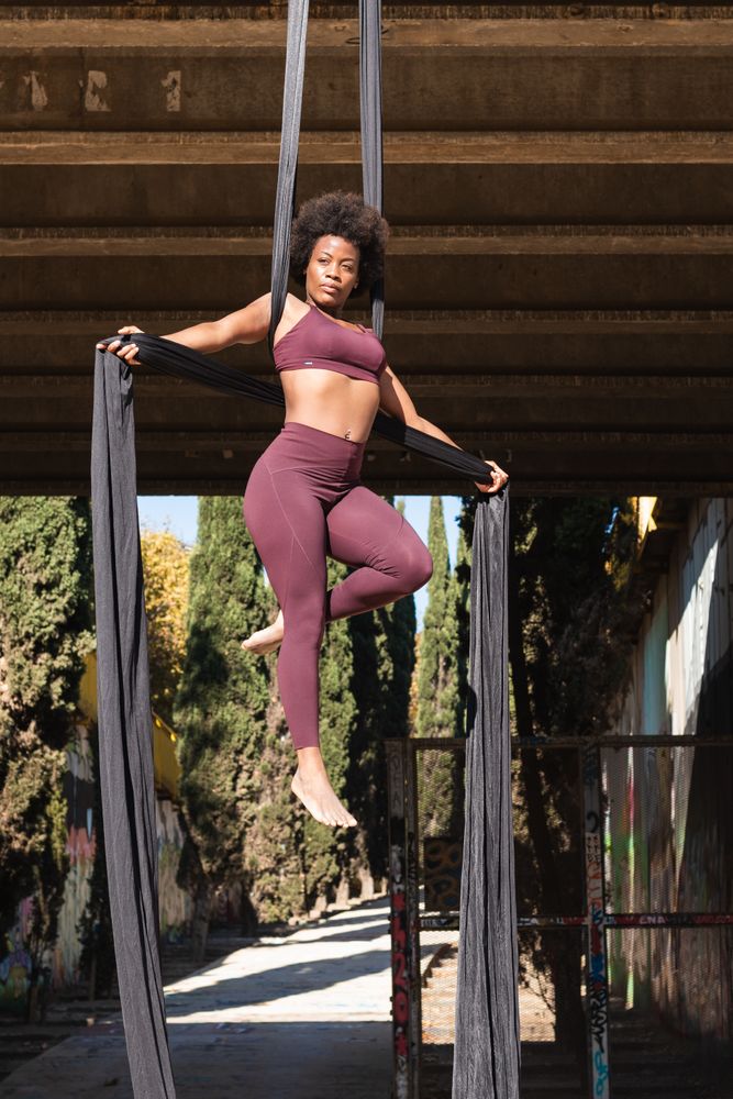 Slim woman doing yoga with aerial silks in city