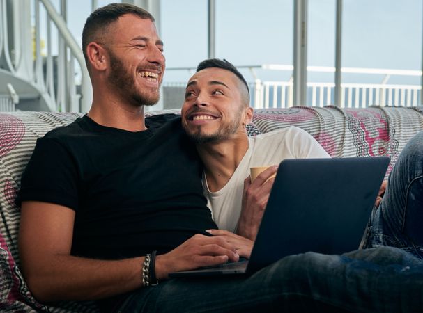 Happy gay couple using laptop at home