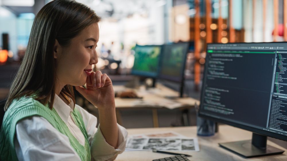 Female Asian Game Programmer Coding On Desktop Computer In Game Development Studio Diverse Office.
