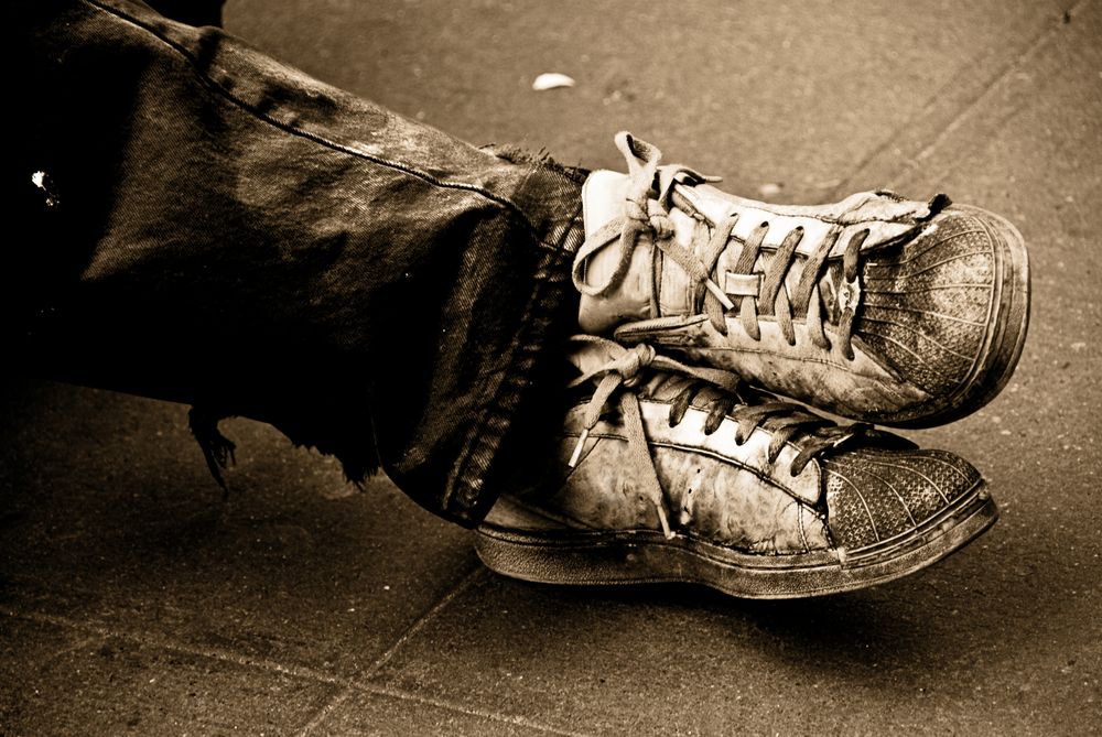 Worn out dirty sneakers of person sitting outside