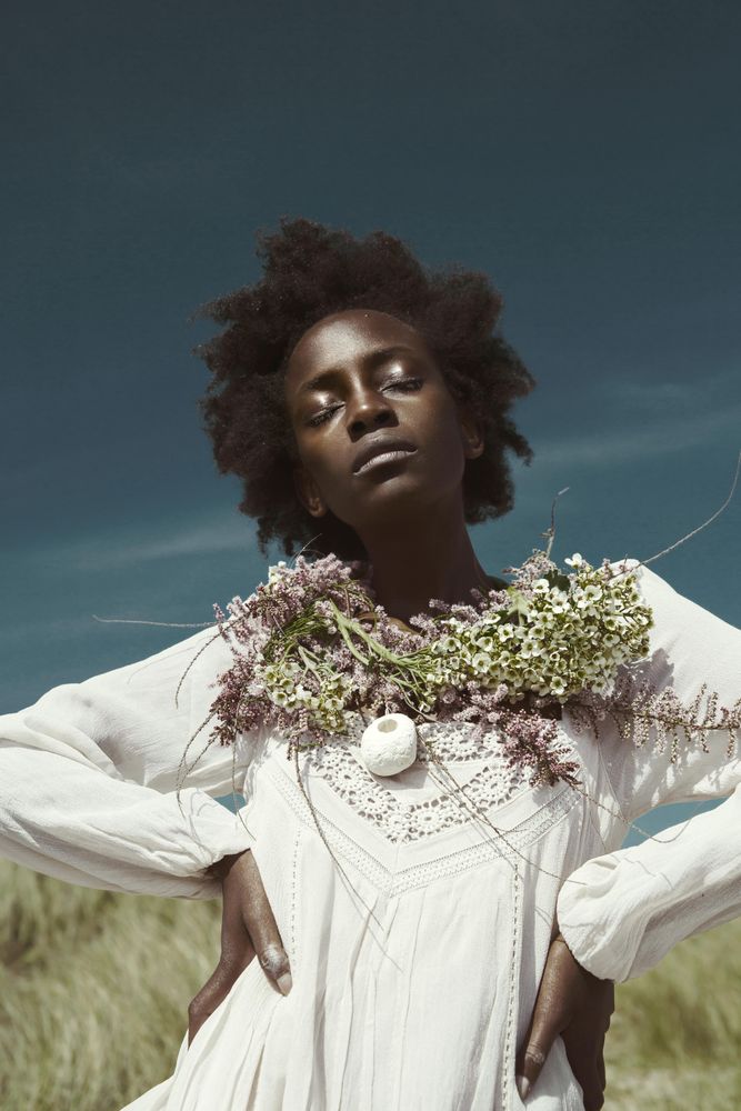 Woman wearing light dress and floral wreath standing outdoor