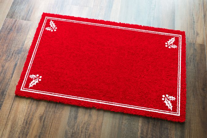 Blank Holiday Red Welcome Mat With Holly Corners On Wood Floor Background