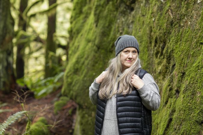 Woman posed confidently next to a mossy rock wall