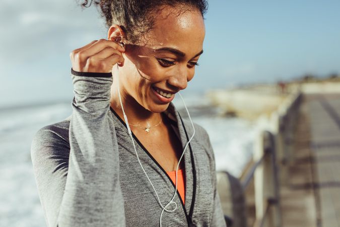 Healthy young woman listening to music while exercising at the promenade