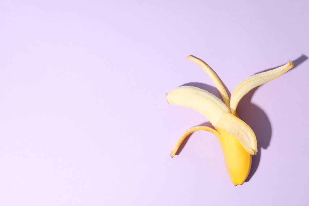 Opened banana on violet background. Fresh fruit
