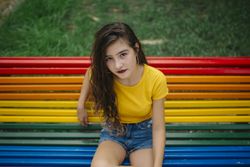 Cheerful woman sitting on rainbow bench